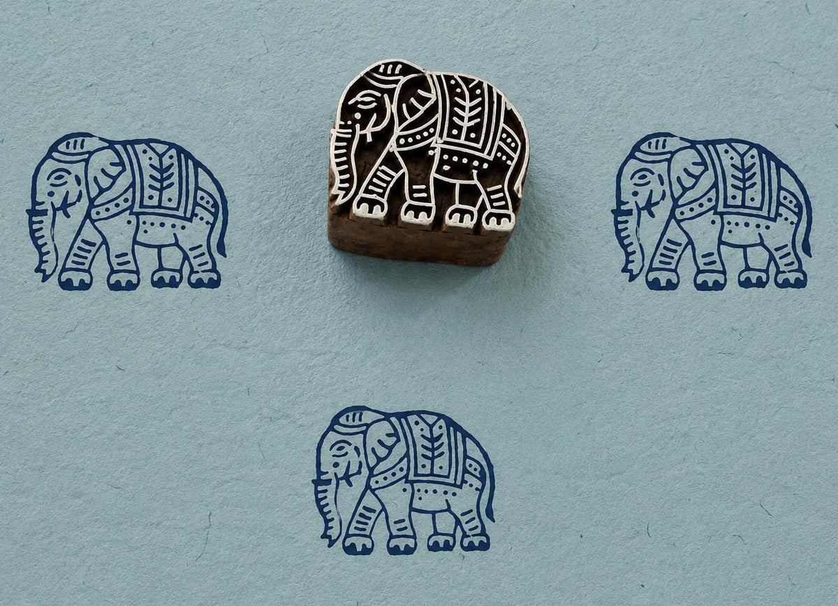 Hand carved Royal Elephant wood block stamp with blue elephant impressions on handmade textured paper