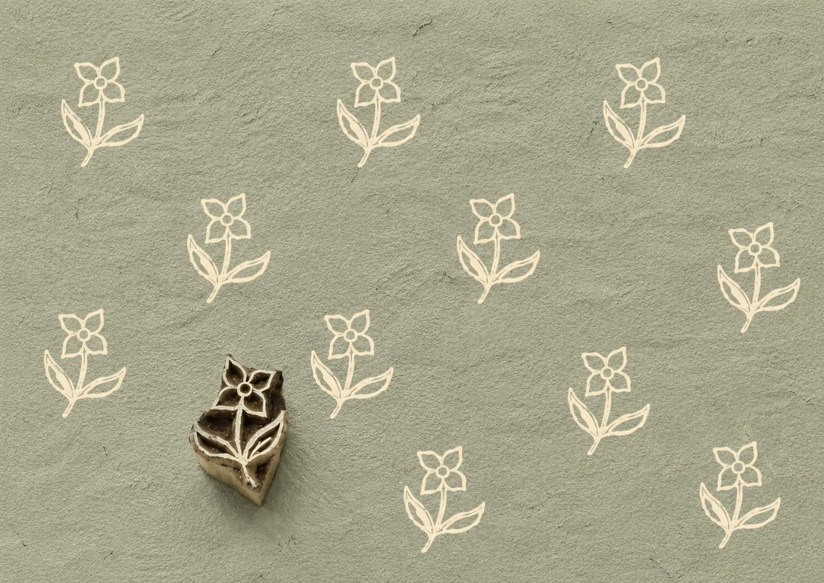 Hand carved Indian wooden printing block featuring a simple folk wildflower motif stamped on sage green handmade paper, ideal for fabric printing, pottery decoration, clay work, and paper crafts.