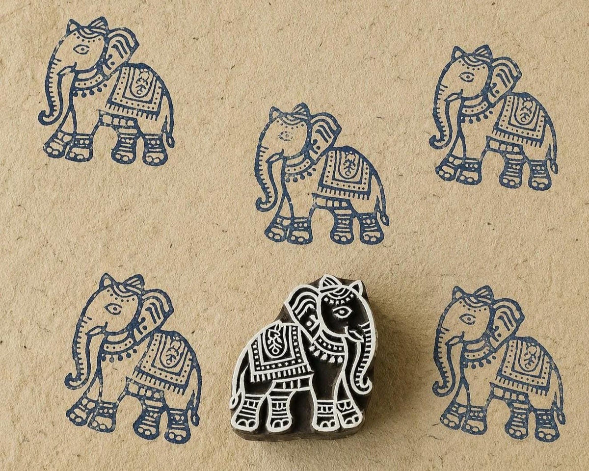 Hand-carved wooden Indian elephant printing block with repeated navy blue elephant impressions on handmade paper, traditional textile stamp.
