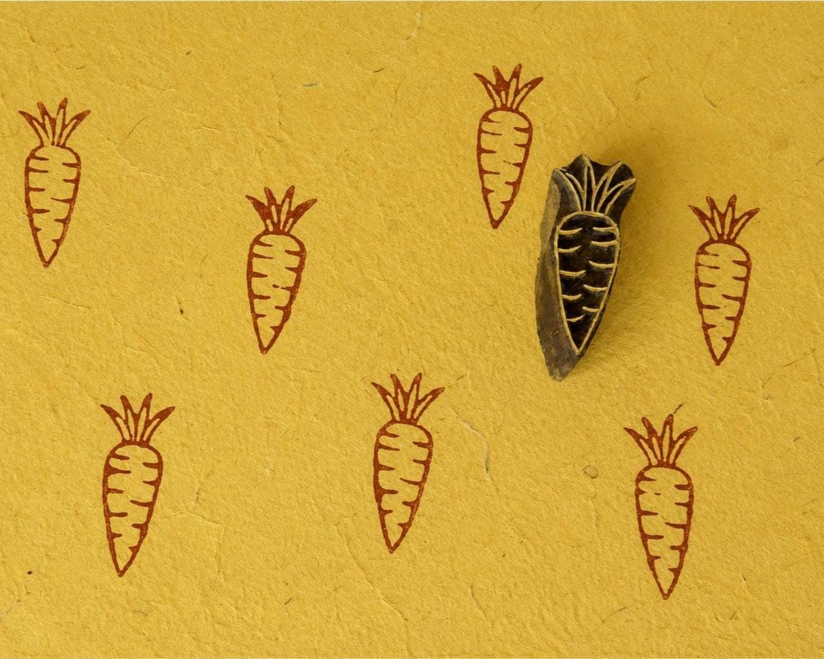 Hand-carved wooden carrot printing block with repeated carrot impressions on mustard handmade paper. Perfect for fabric printing, paper crafts, journaling, and DIY projects.