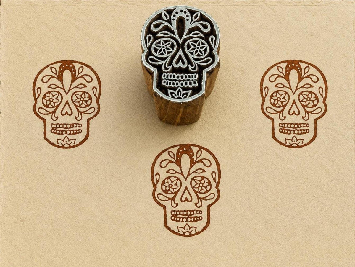 Hand-carved Sugar Skull wood block stamp with detailed brown calavera impressions on handmade cream paper.