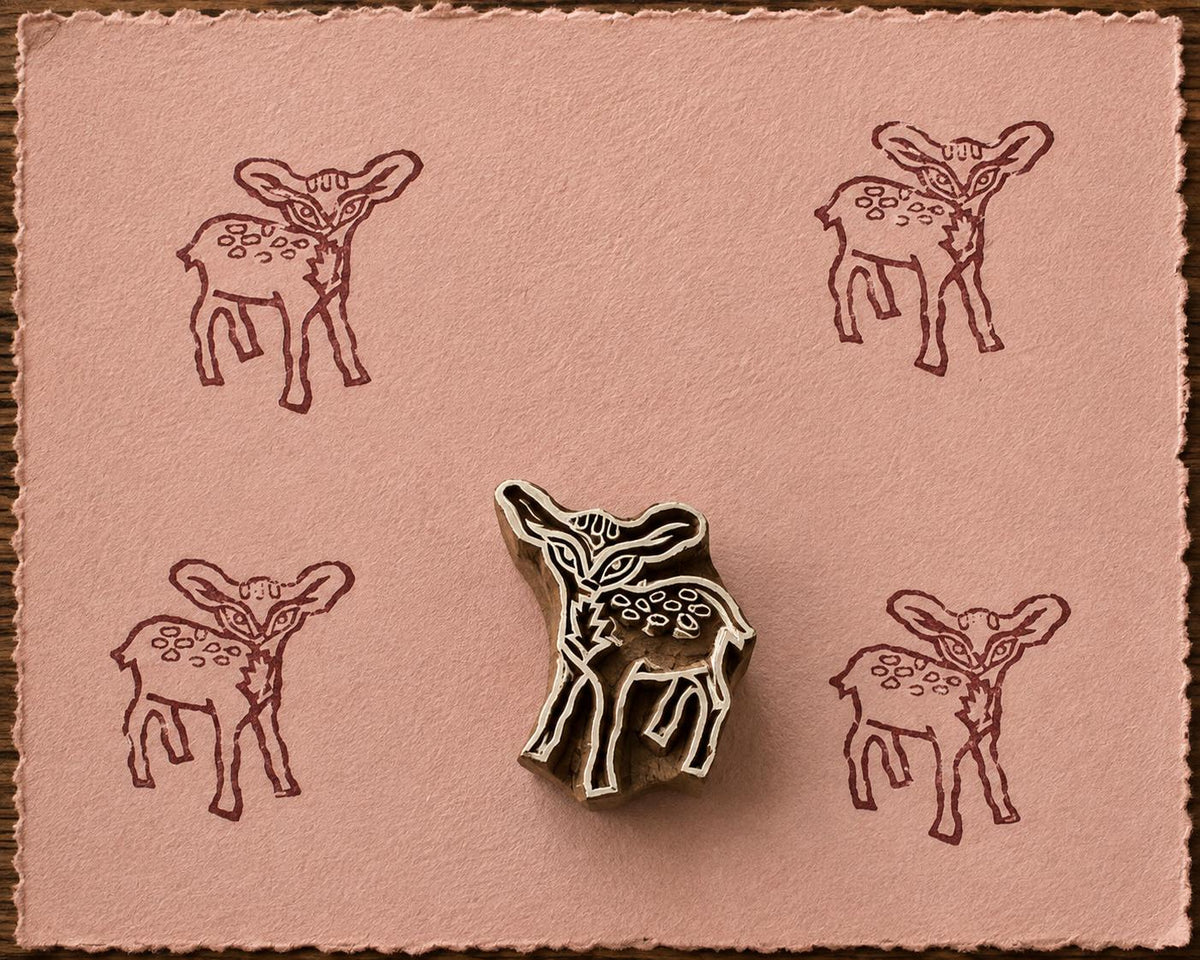 Hand-carved Woodland Fawn wood block stamp with brown deer impressions on blush handmade paper.