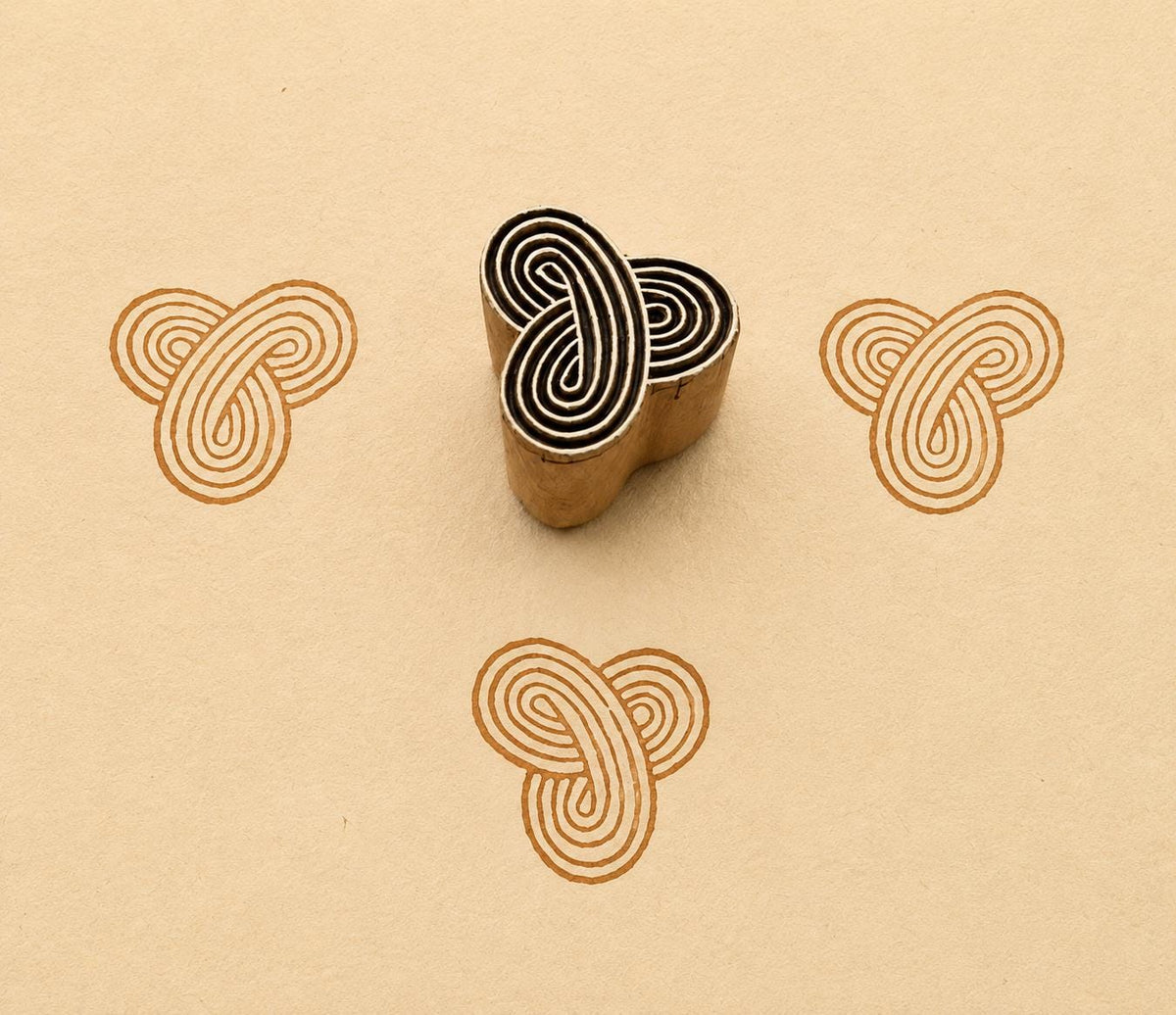 Hand carved Infinity Knot wooden printing block with interlocking geometric pattern printed on handmade paper for fabric printing, textile design, pottery, clay and paper crafts.
