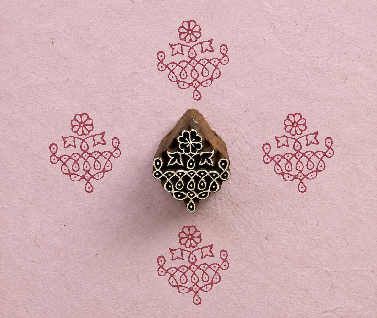 Hand carved Indian textile printing block with an ornate Temple Garland motif, shown with four red impressions on handmade pink paper.