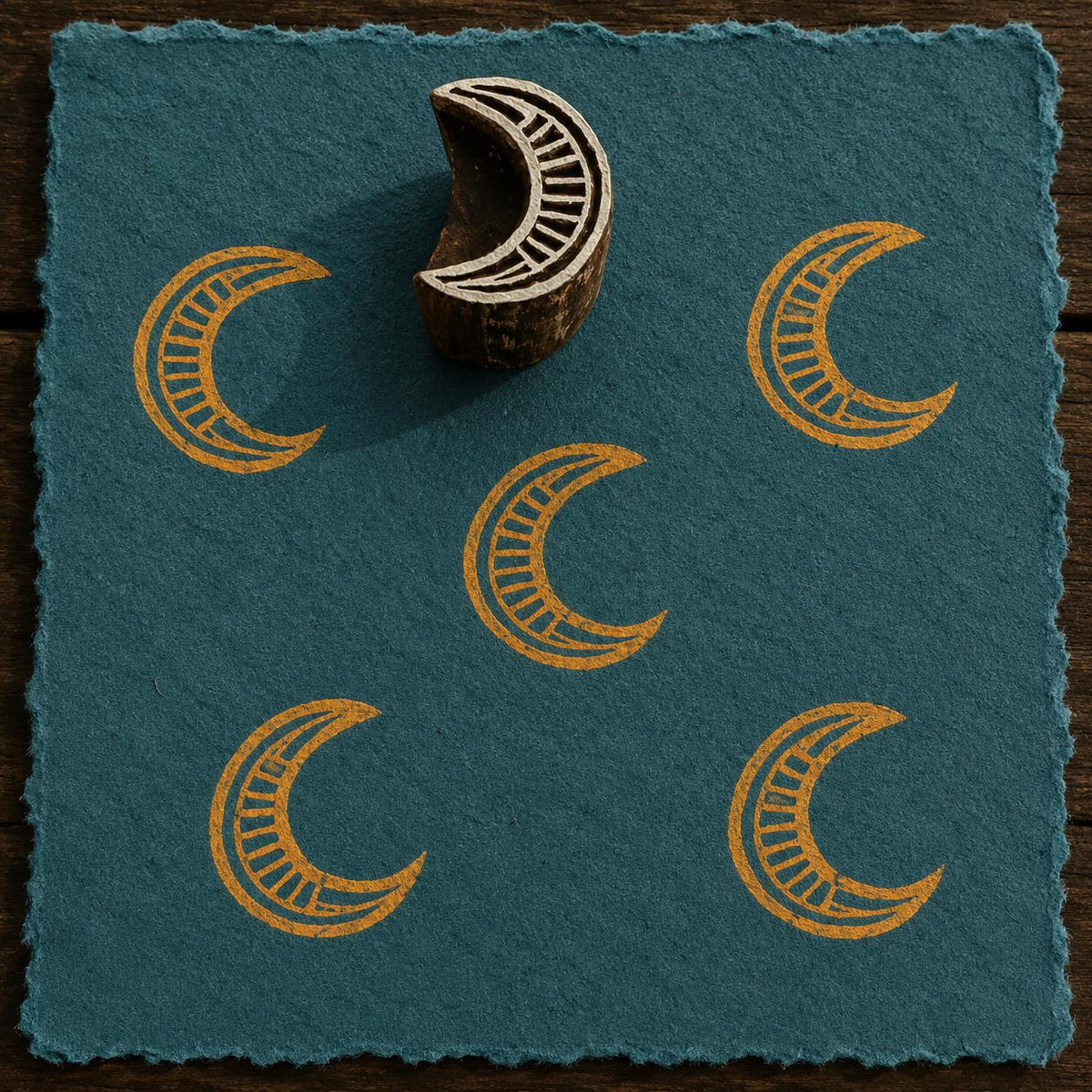 Hand-carved Ornate Crescent Moon wooden printing block with golden crescent moon impressions on textured blue handmade paper.