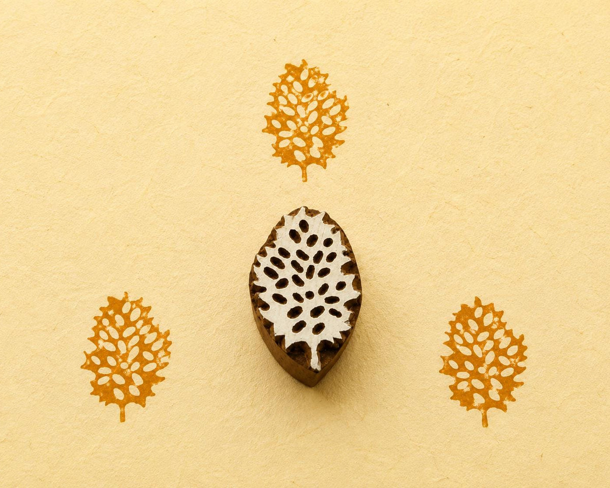 Hand carved Indian wooden printing block featuring an intricate lace leaf botanical design with mustard yellow prints on handmade paper.