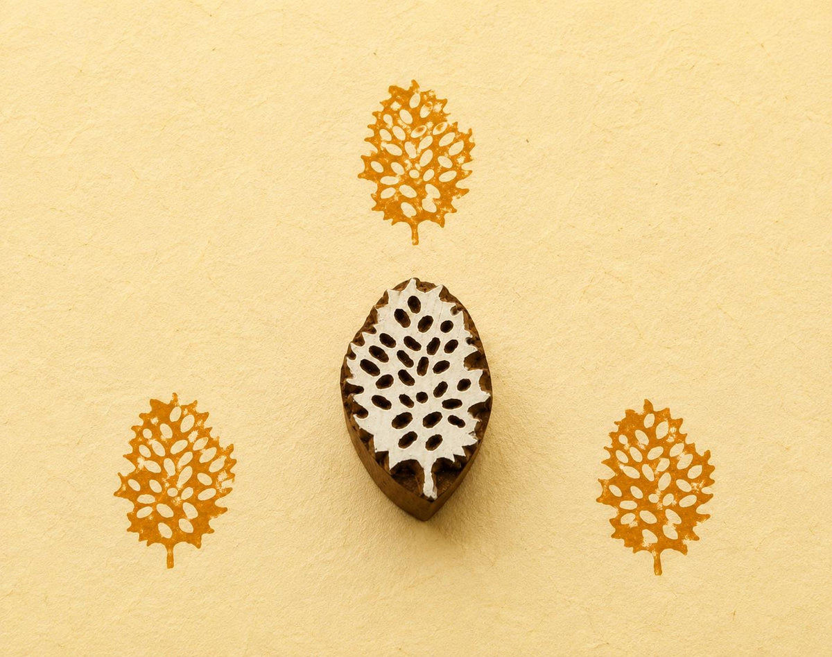 Hand carved Indian wooden printing block featuring an intricate lace leaf botanical design with mustard yellow prints on handmade paper.