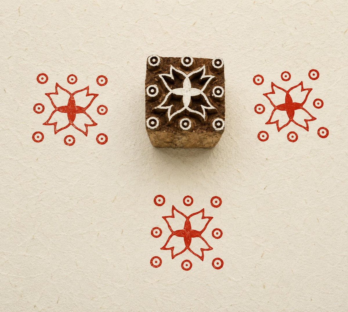 Hand carved Indian wooden textile printing block featuring a Temple Star floral motif with circular accents, stamped in red on handmade paper.