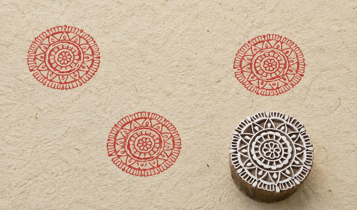 Hand carved wooden stamp creating detailed circular mandala pattern on fabric
