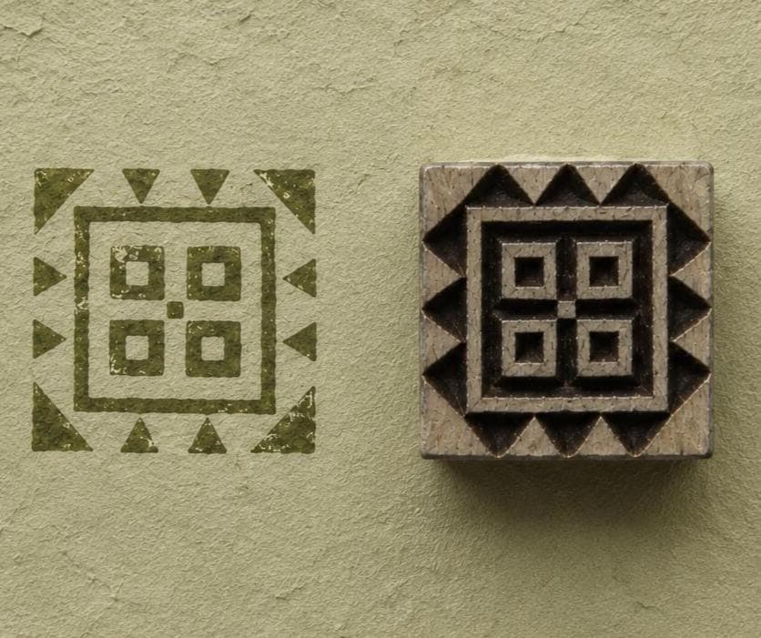 Hand carved geometric square wood block stamp with olive green impression on handmade pale green paper