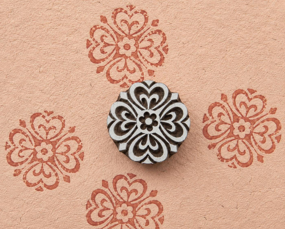 Six petal geometric wooden stamp with a symmetrical ornamental design shown on handmade paper.
