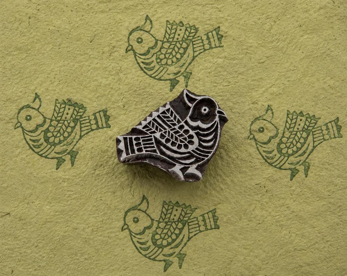 Carved decorative bird woodblock with repeating green bird prints on handmade paper