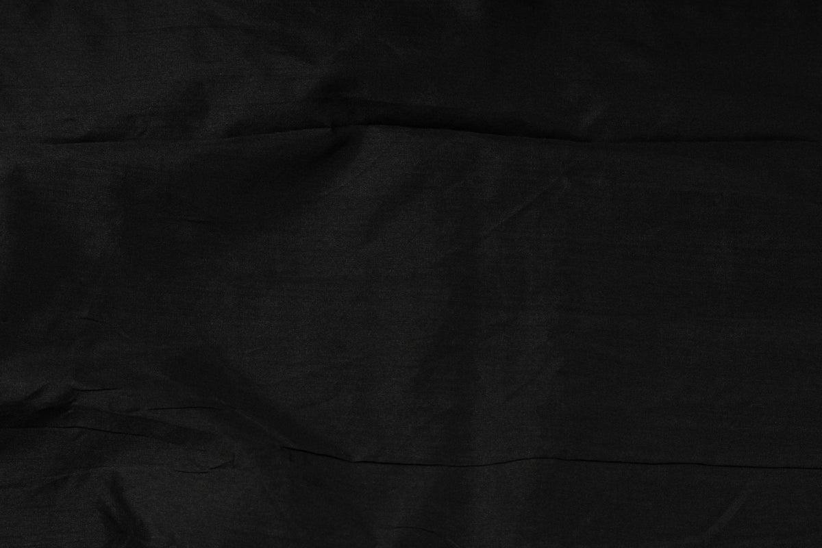 Draped jet black faux dupioni fabric showing its folds, texture and subtle sheen.