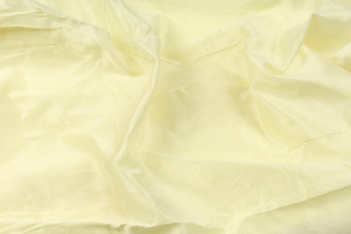 Vanilla cream faux silk fabric arranged in flowing folds to show its subtle shine and drape.