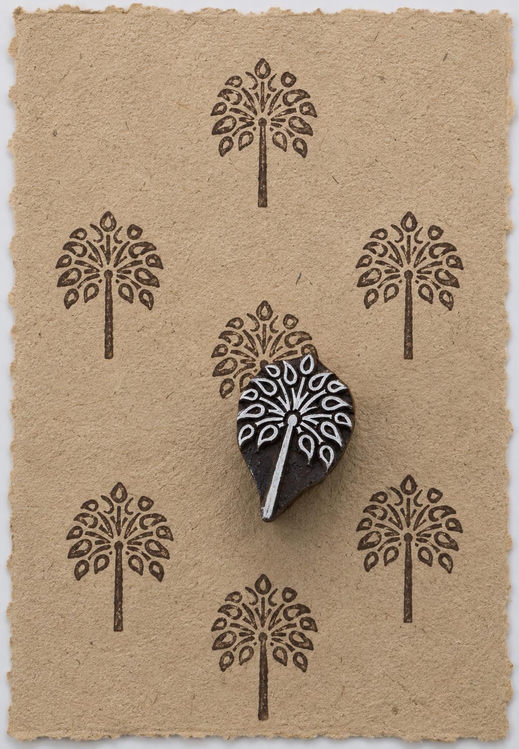 Hand carved leaf tree wooden printing block shown on handmade paper with repeated botanical impressions