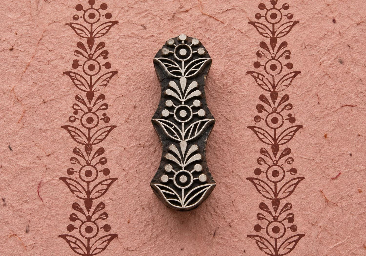 Hand carved wooden Floral Totem printing block with a repeating floral border printed on textured pink handmade paper.