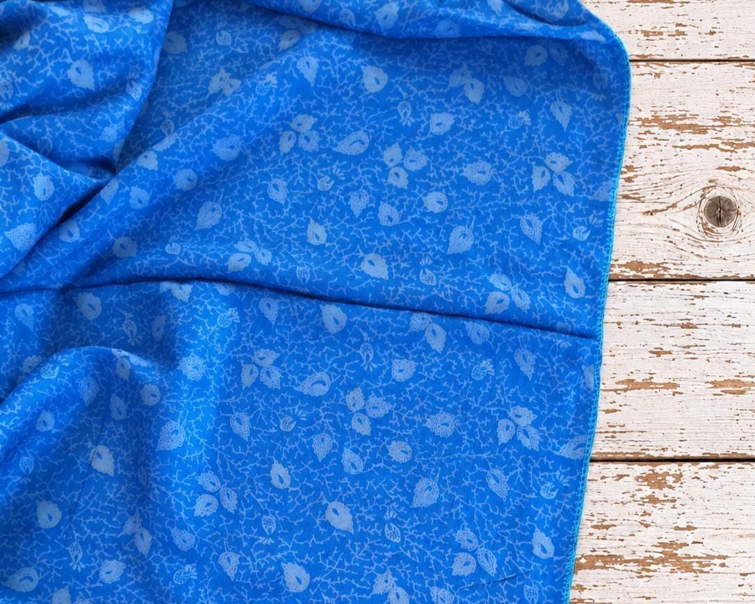 Close-up of vintage blue sari silk showing detailed lighter blue floral paisley and botanical motifs