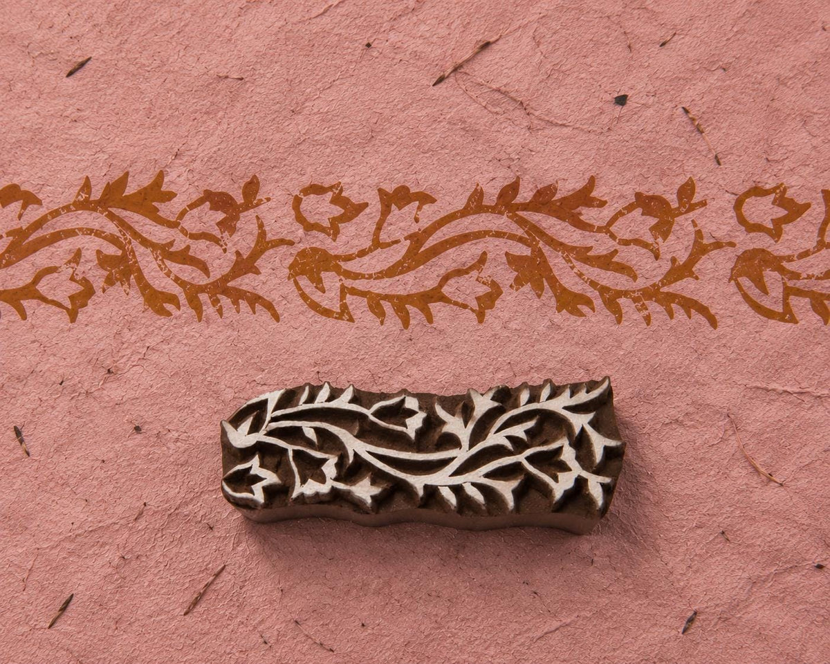 Meandering Vine Border hand carved wooden printing block with a flowing floral vine impression on handmade pink paper.