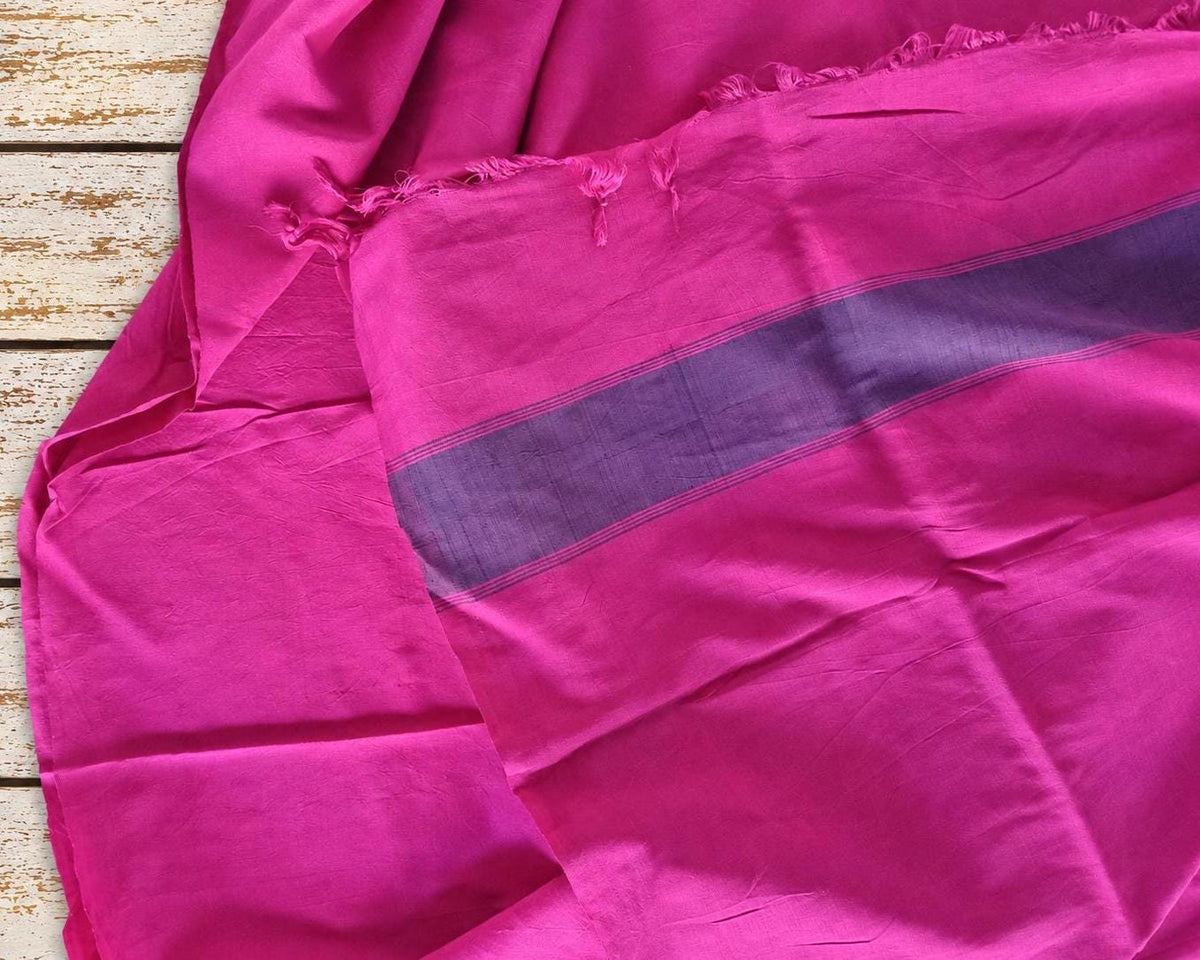 Fuchsia pink silk textile with purple striped border and fringed edge, shown draped to reveal its sheen and texture