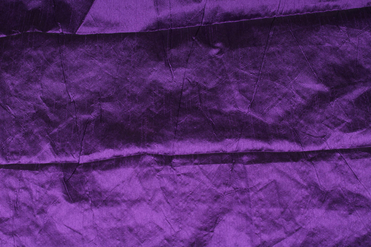 Purple faux silk fabric draped in soft folds with deep violet highlights