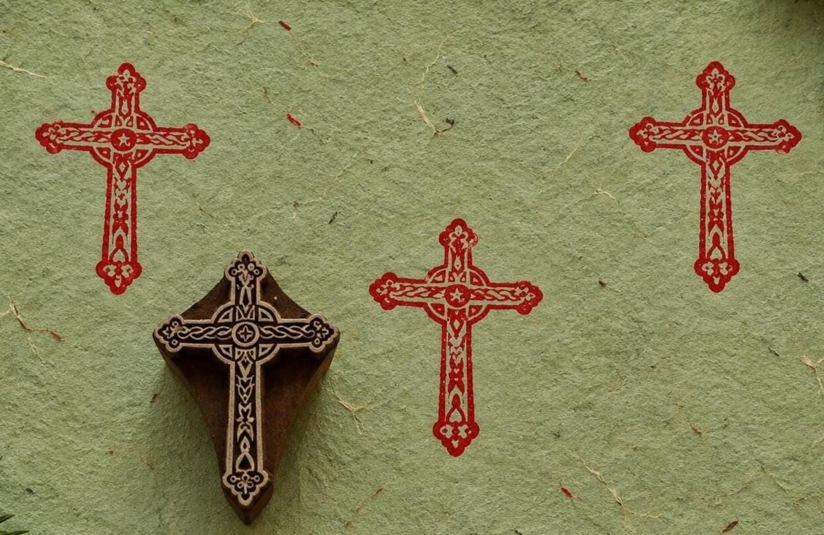 Hand carved cross stamp used to create a decorative religious motif on handmade paper.