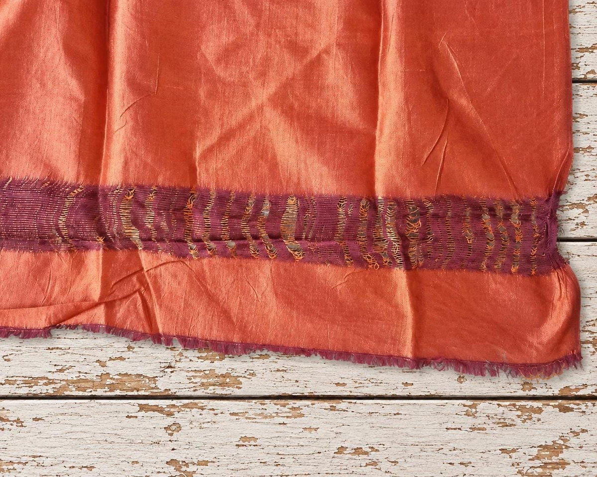 close view of woven plum purple and orange border with loose frayed threads