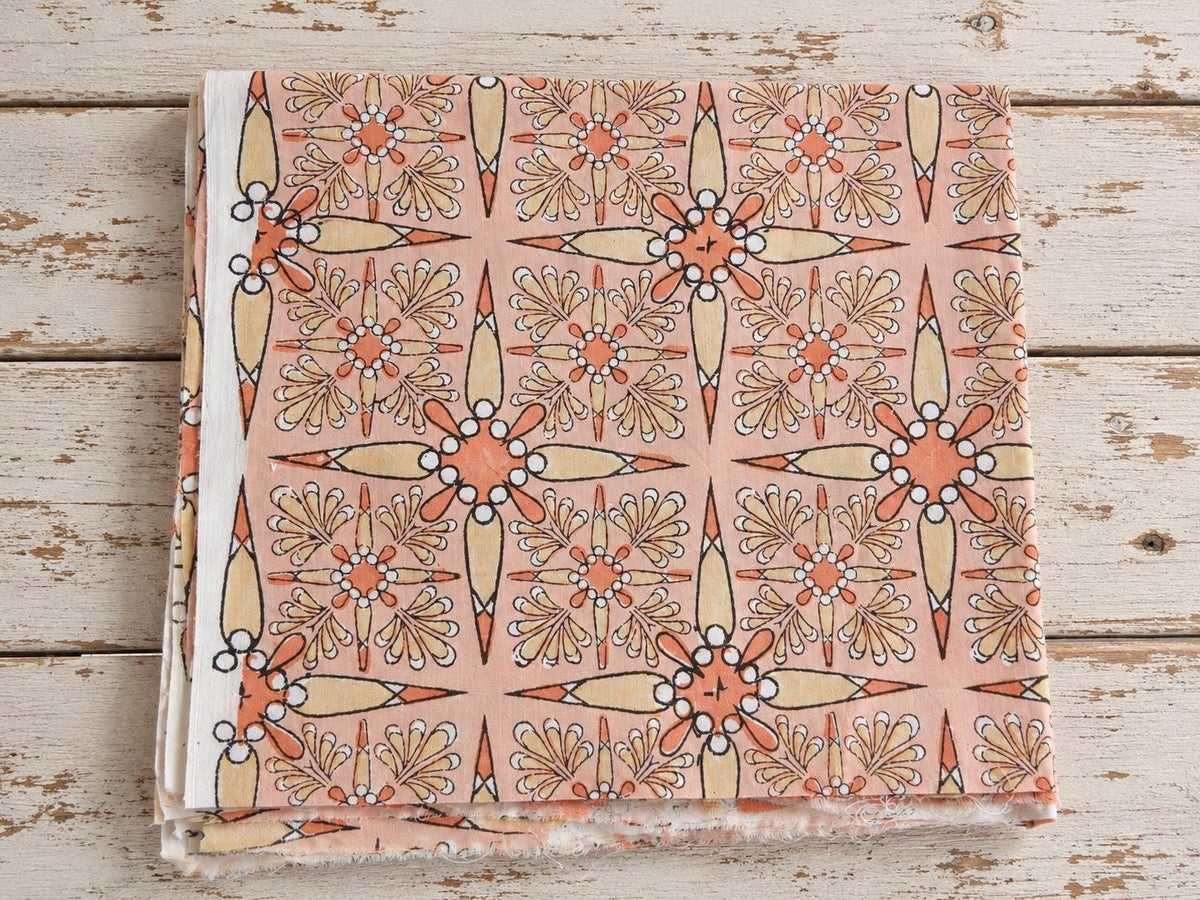 Folded peach mulmul cotton fabric with Vintage Starburst block print