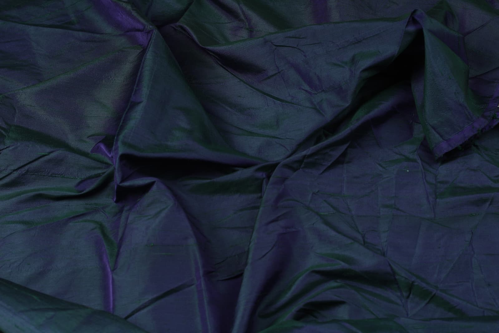 Peacock Blue Dupion Silk Fabric displayed in flowing folds revealing iridescent blue, teal, and violet highlights with natural silk texture