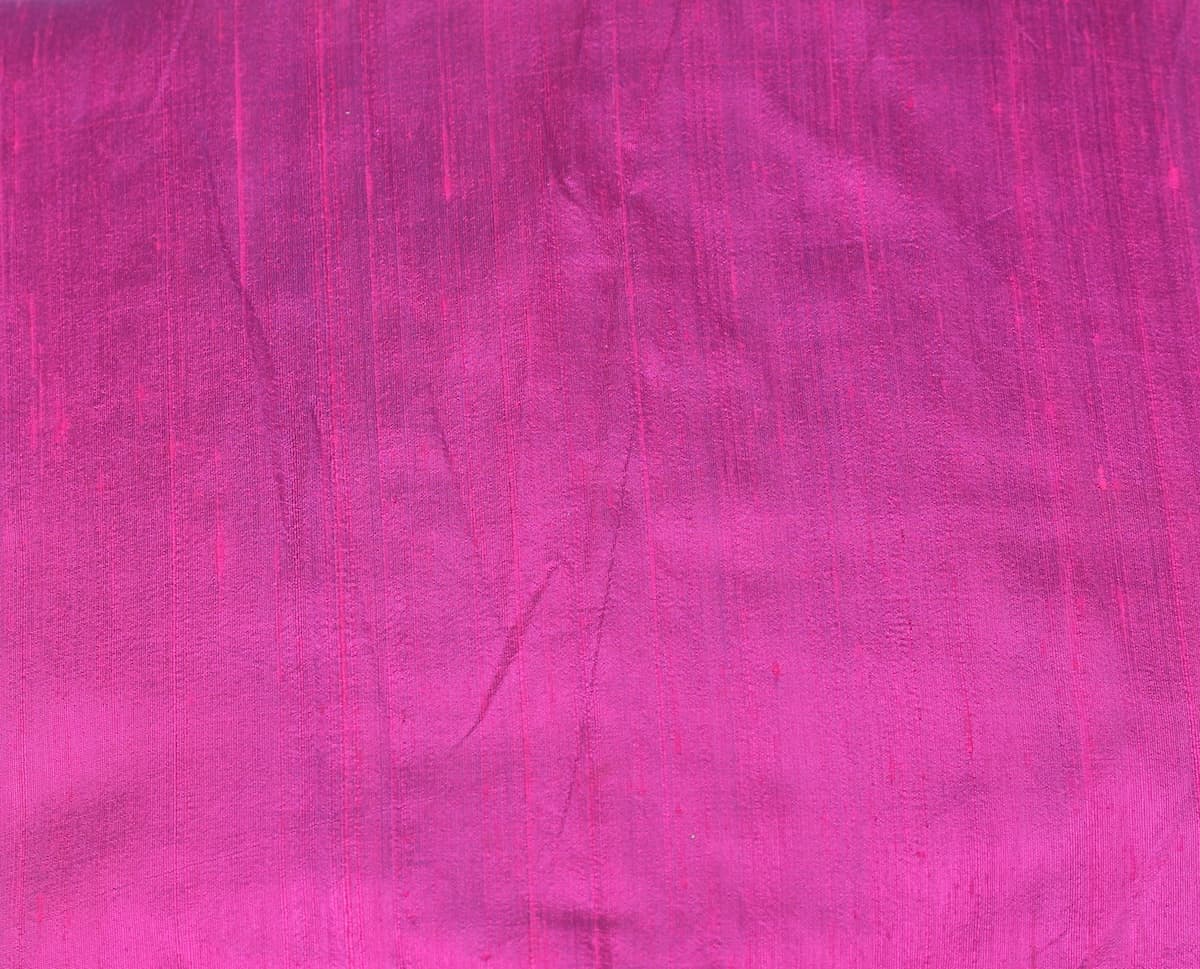 Close-up of Fuchsia Magenta dupion silk fabric showing vibrant pink colour, natural raw silk texture, and characteristic silk slubs