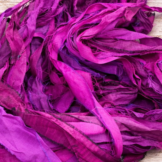 Detailed view of recycled sari silk ribbon in vibrant orchid, magenta and purple shades.
