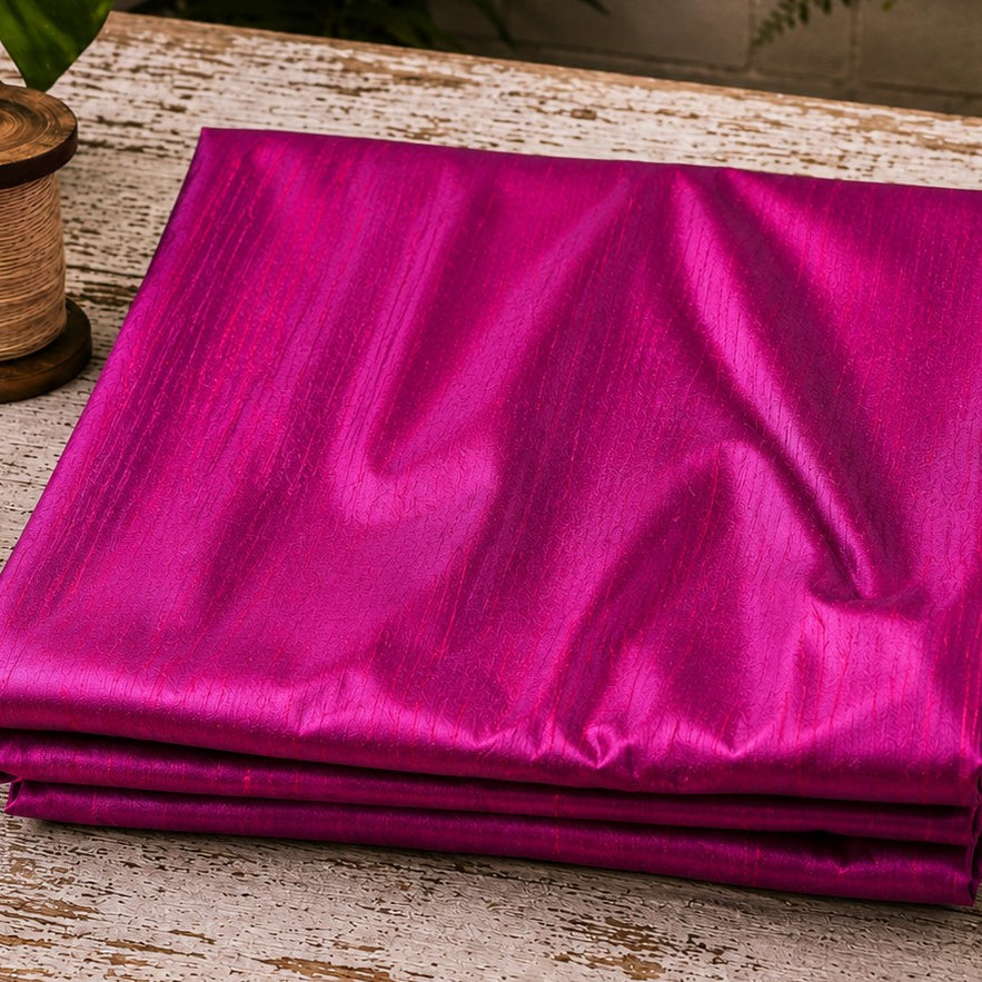 Fuchsia Magenta dupion silk fabric folded on a tabletop showing vibrant pink and magenta iridescent tones with natural raw silk texture