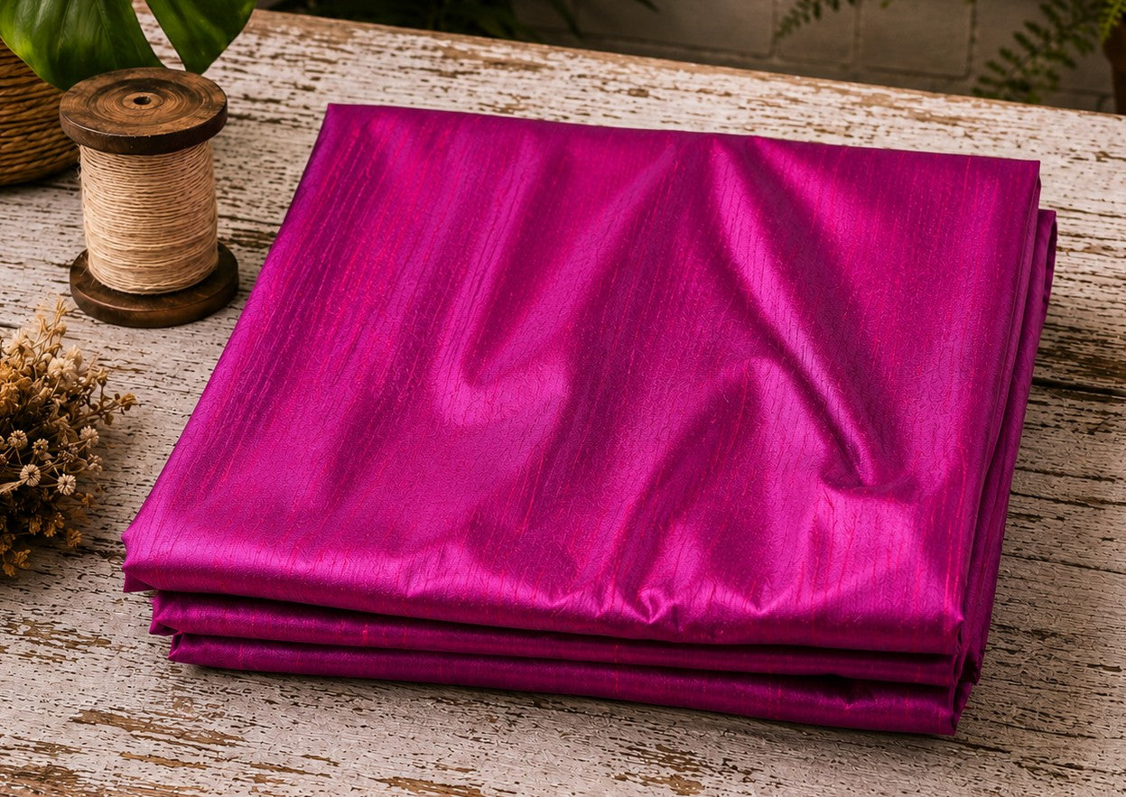 Fuchsia Magenta dupion silk fabric folded on a tabletop showing vibrant pink and magenta iridescent tones with natural raw silk texture