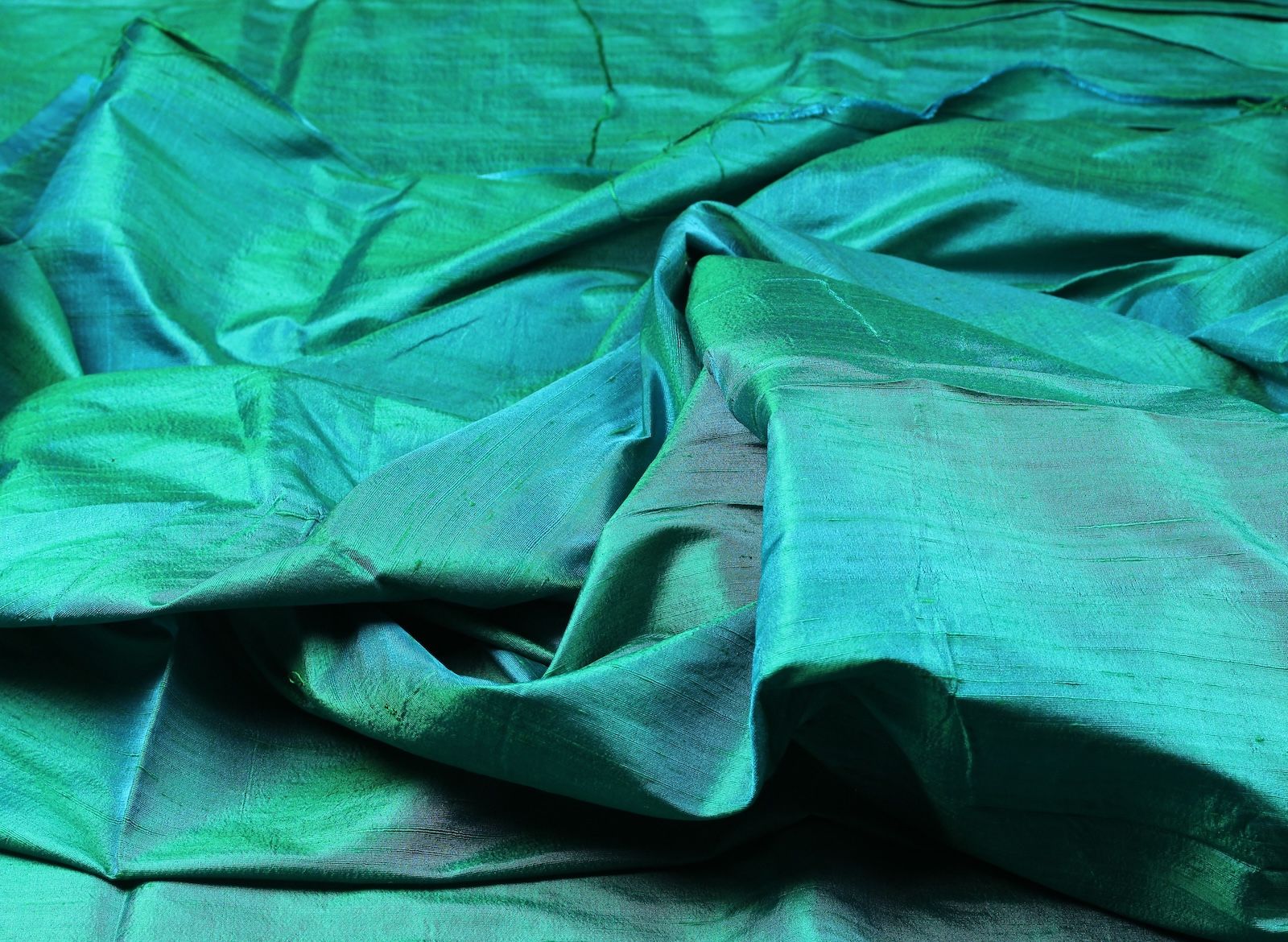 Peacock teal raw silk fabric draped to show shimmer and texture