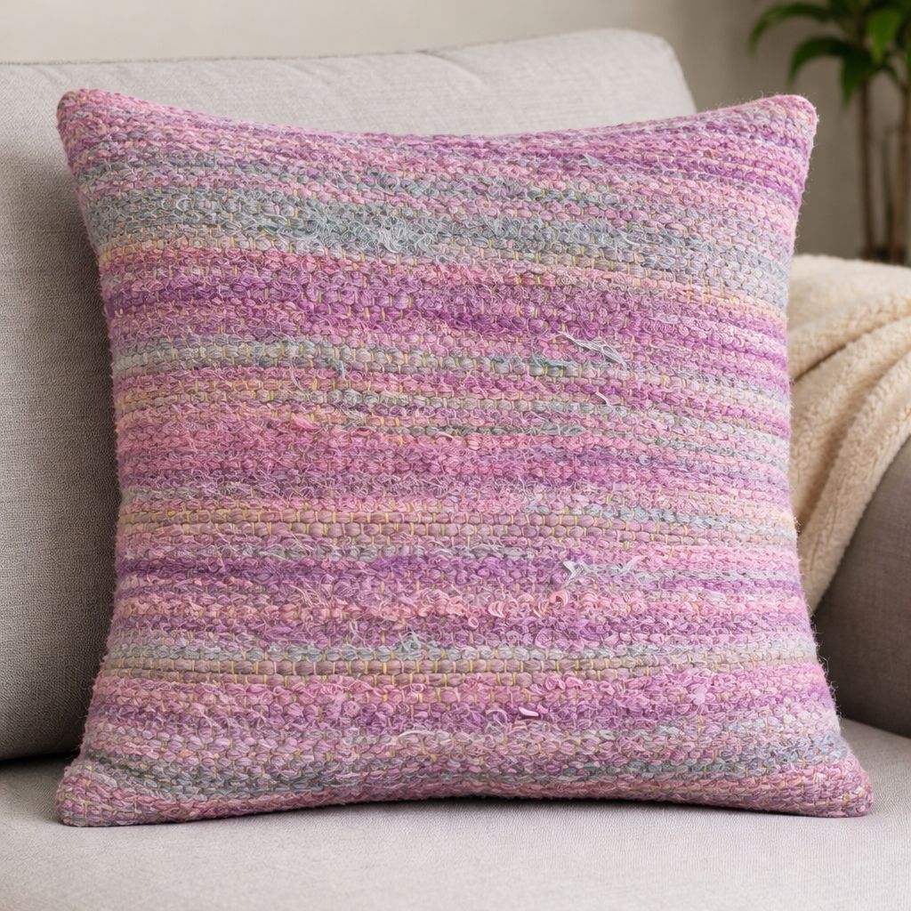 Decorative cushion made from handwoven sari ribbon fabric in pastel pink and lilac tones.