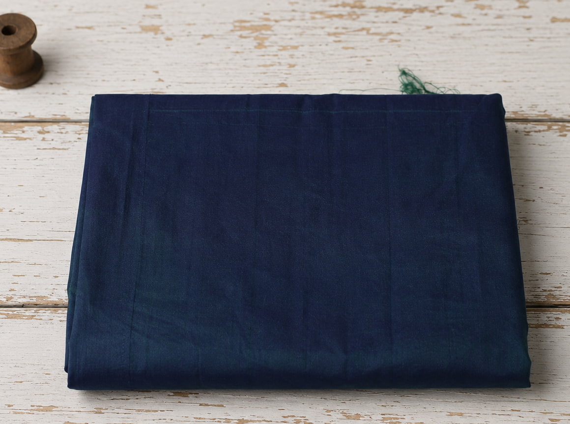 Peacock Blue Dupion Silk Fabric folded to display its iridescent blue, teal, and violet tones with natural silk texture and luxurious sheen