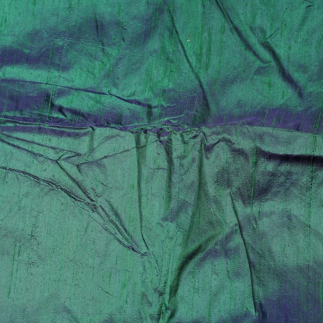 Peacock Lagoon dupion silk fabric draped to display iridescent blue-green sheen, natural slubs, and luxurious raw silk texture