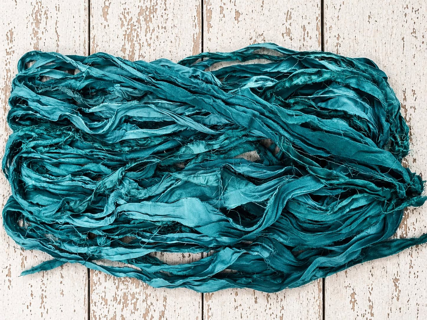 Close-up texture of Peacock Lagoon recycled silk ribbon yarn with frayed edges