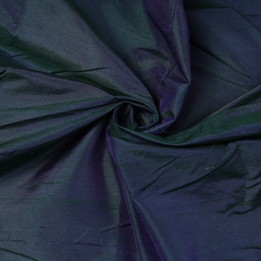 Peacock Blue Dupion Silk Fabric arranged in elegant swirling folds highlighting its colour-shifting sheen and rich peacock-inspired tones