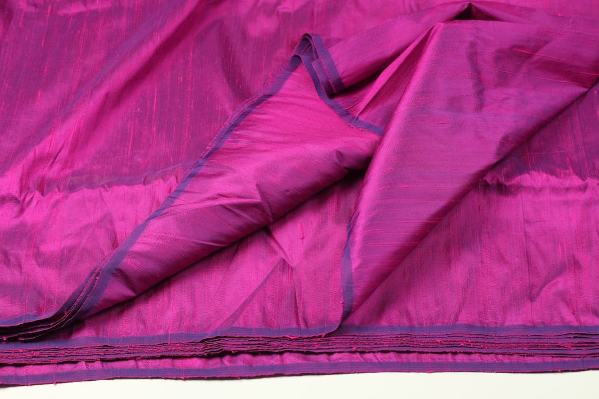 Fuchsia Magenta dupion silk fabric draped open to display colour variation, iridescent sheen, and natural slub texture