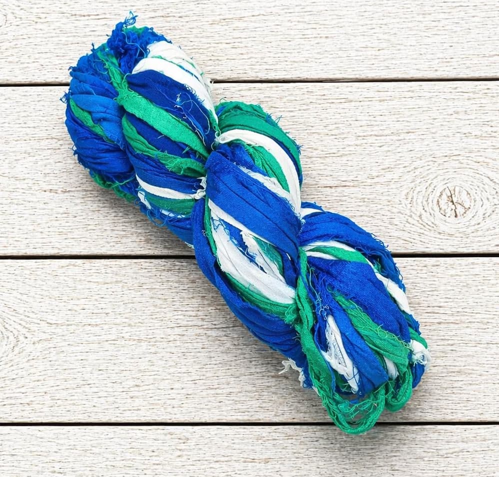 Single skein of Ocean Breeze sari silk ribbon yarn in cobalt blue, green and white shades