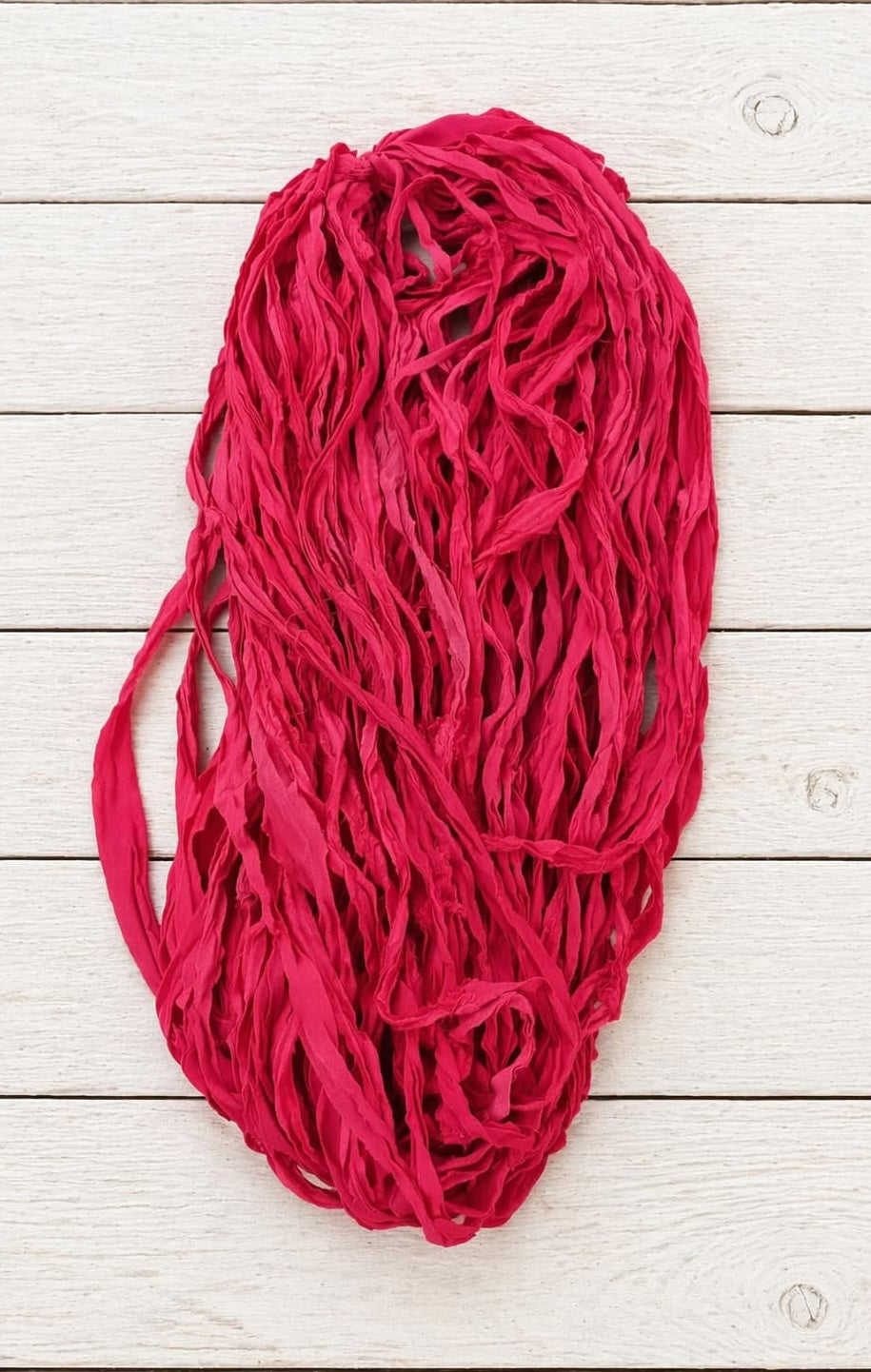 Loose strands of bright pink sari silk ribbon yarn