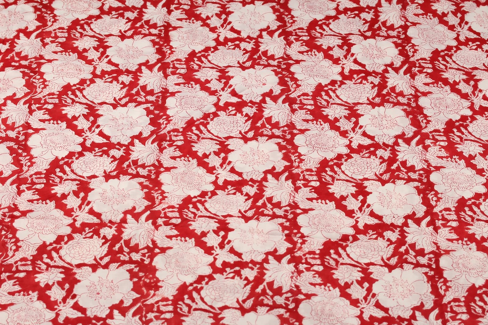 Scarlet red floral block print cotton fabric featuring repeating ivory flowers and botanical motifs