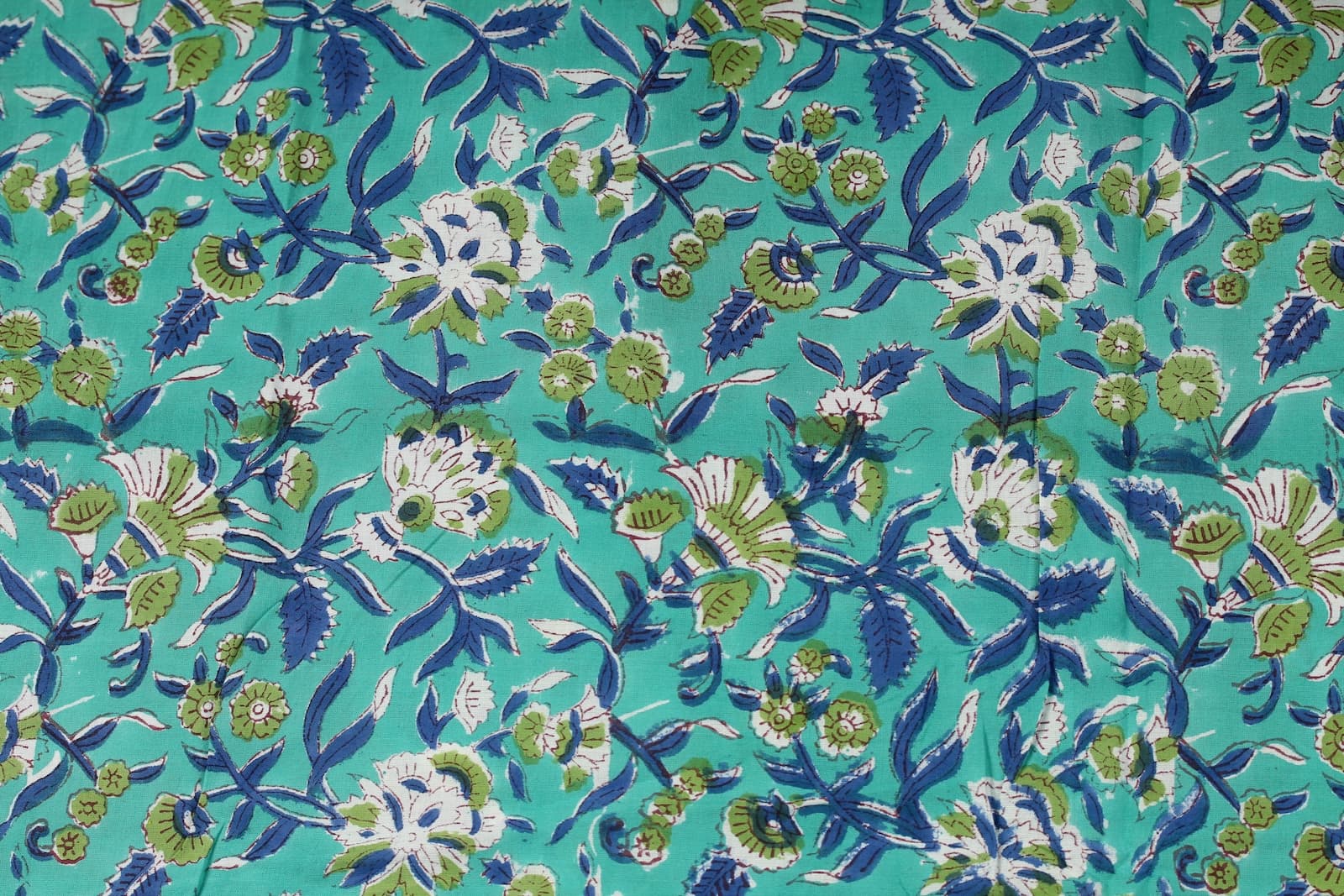 Close-up of Seafoam Wildflower Trail block printed cotton fabric showing floral motifs, navy vines, and botanical details