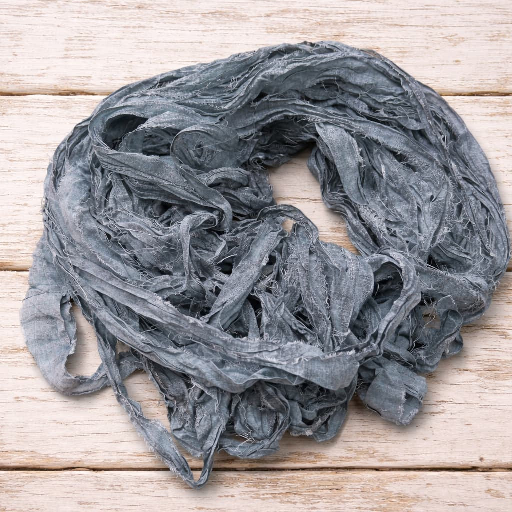 Loose hank of storm grey sari silk ribbon made from reclaimed sari silk fabric.