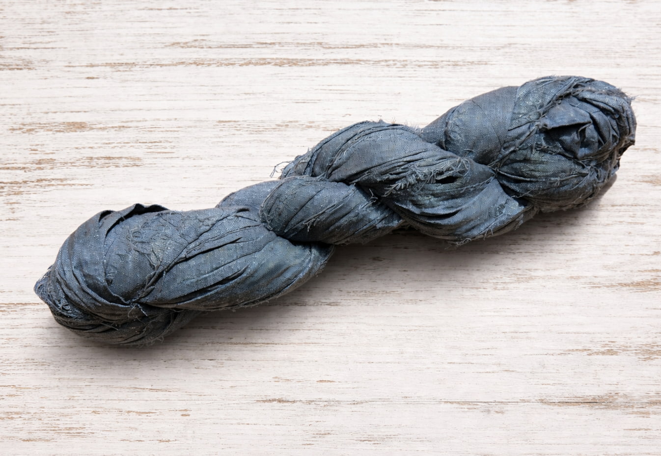 Single storm grey sari silk ribbon skein in a muted grey shade.