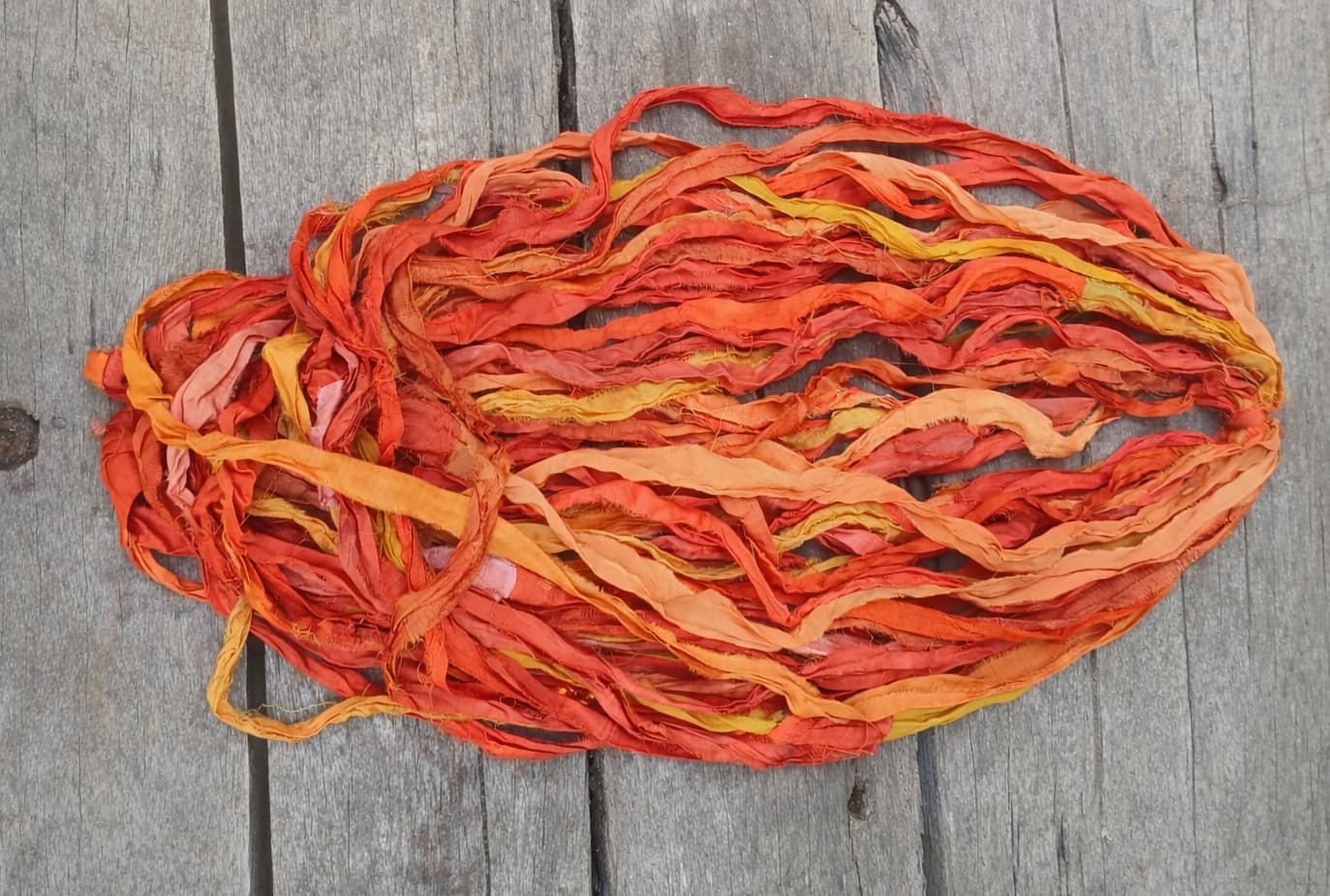 Loose hank of Sunset Mango sari silk ribbon displaying vibrant sunset-inspired colours and texture.