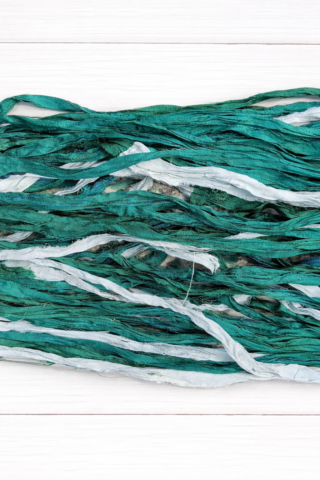 Close up texture of teal and white recycled sari silk ribbon yarn