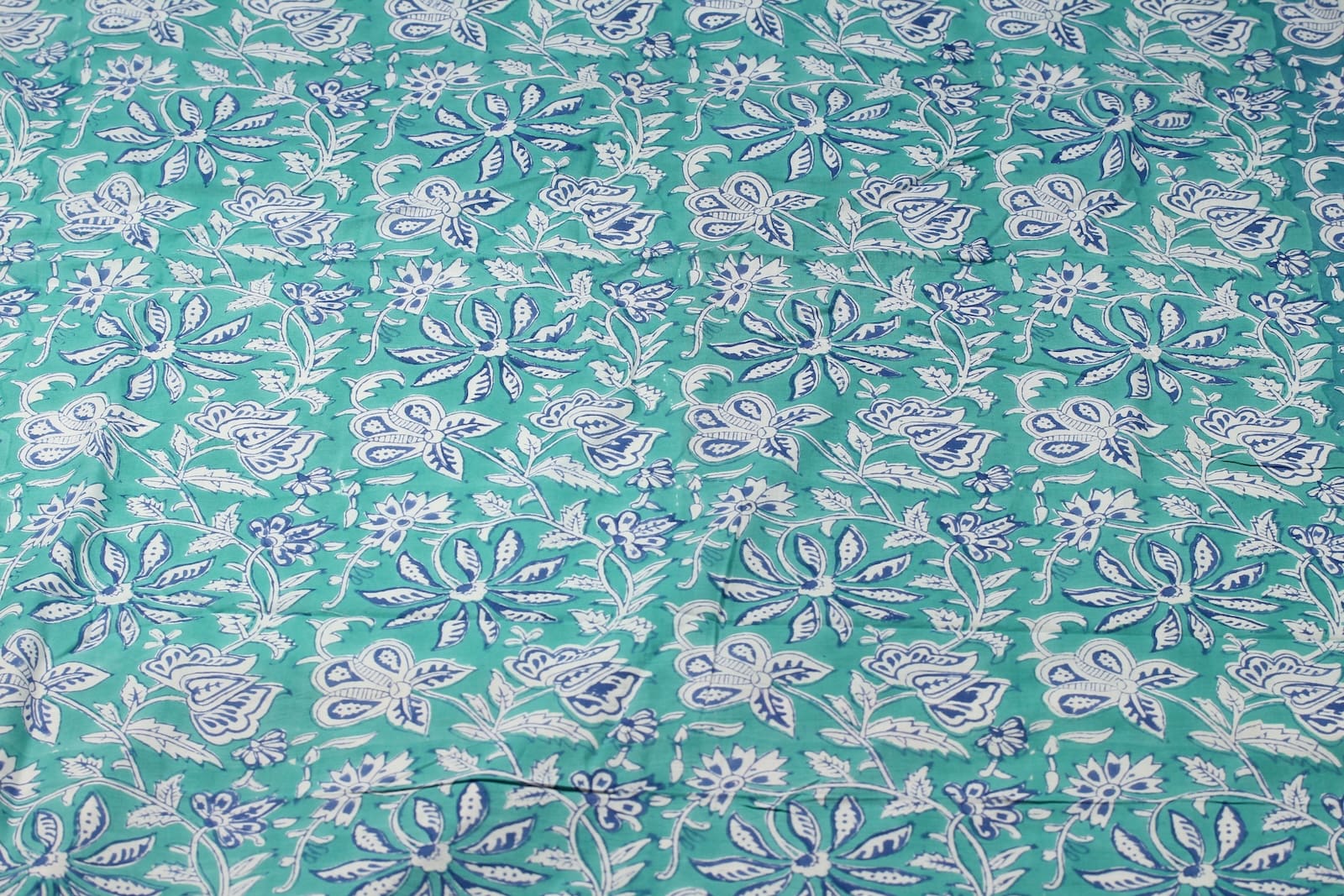 Turquoise cotton fabric with indigo blue and ivory floral vine block print shown as full yardage pattern