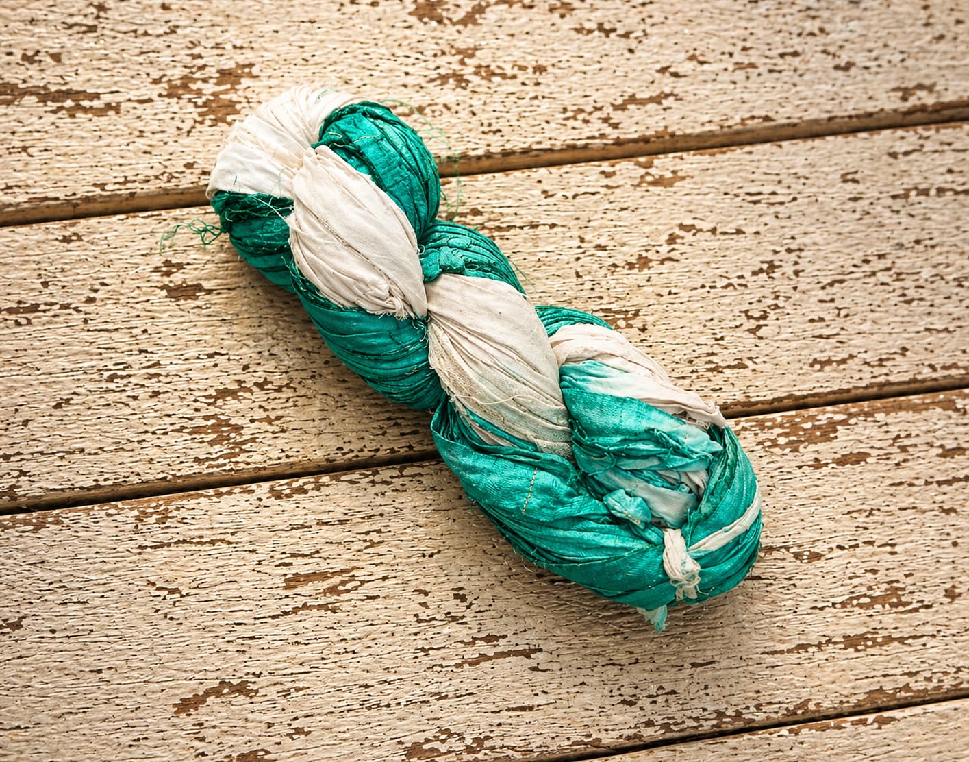 Seafoam and ivory sari silk ribbon yarn skein photographed on rustic wood background