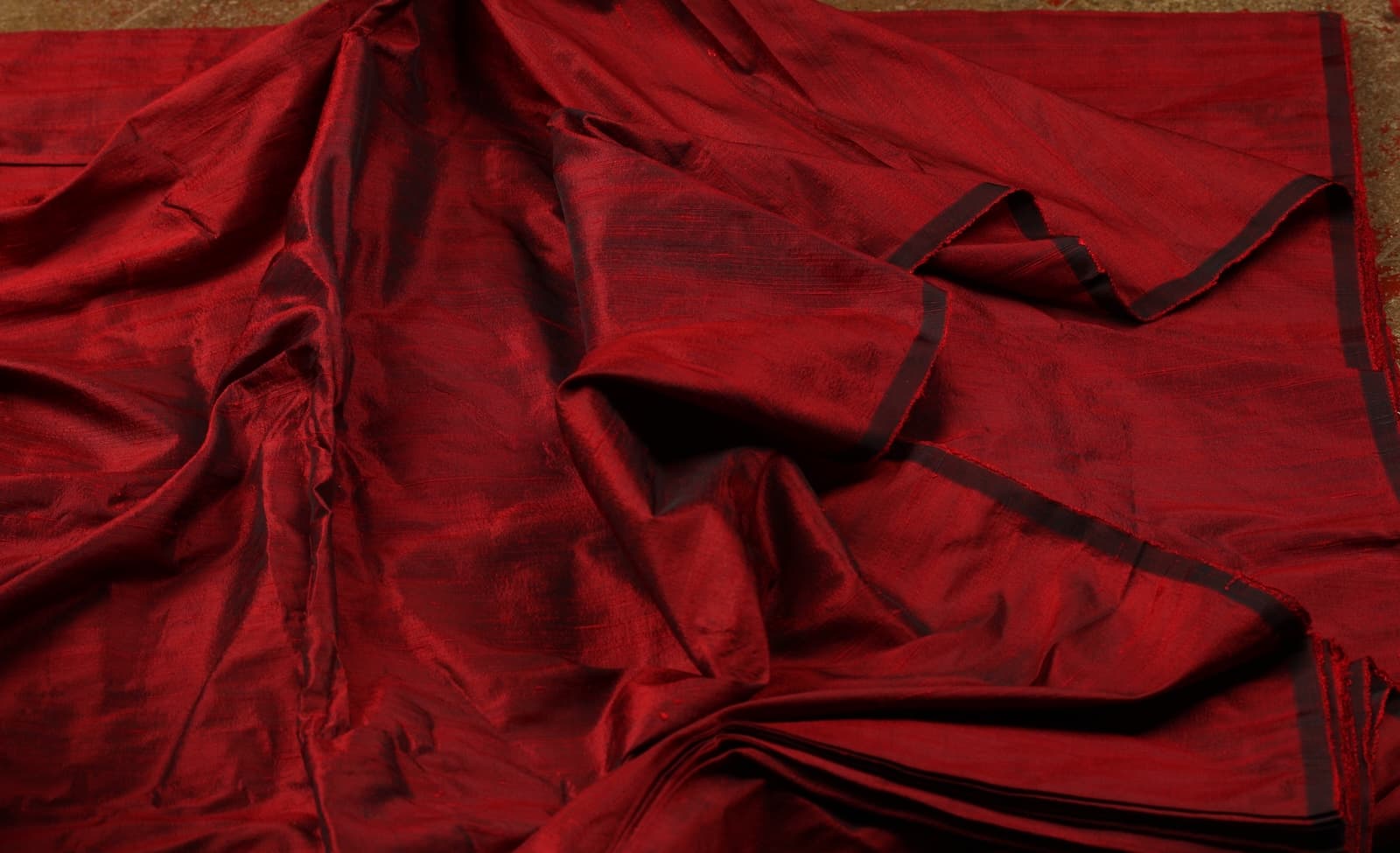 Bordeaux Red Dupion Silk Fabric displayed in flowing folds showing its rich jewel-toned colour and luxurious silk sheen
